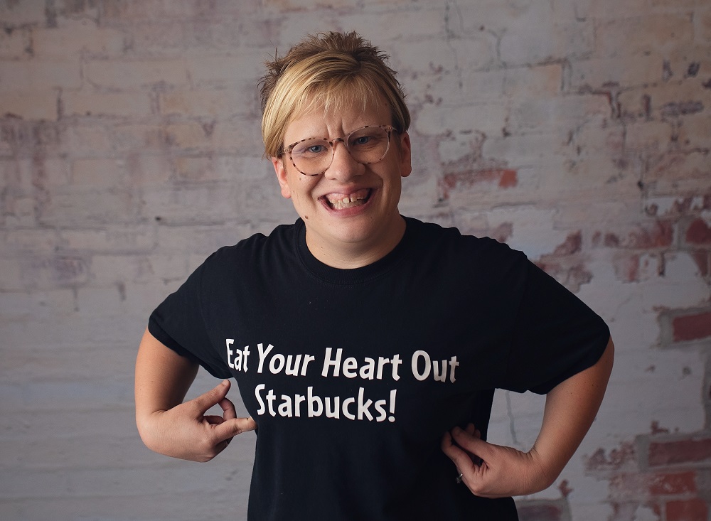 Photograph of Em Lantz wearing a shirt that reads "Eat Your Heart Out Starbucks!"