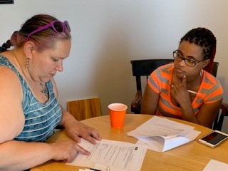 Stepanie-and-SRM-at-table Photograph of Simone Renee Moore and Stephanie sitting at a table examining papers