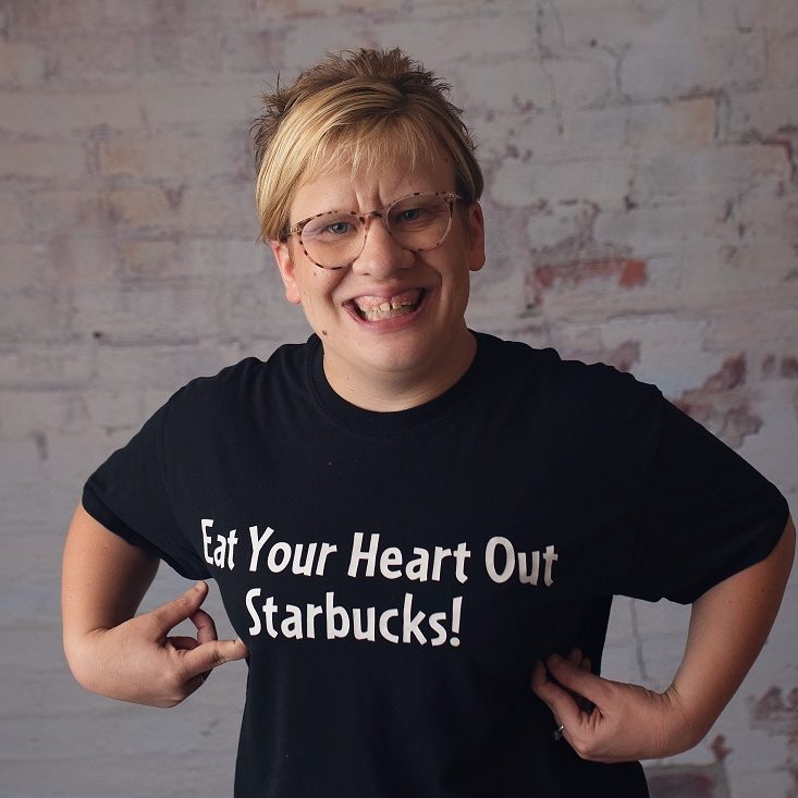 Photograph of Em Lantz wearing a shirt that reads "Eat Your Heart Out Starbucks!"